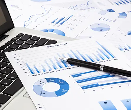 laptop and pen with blue business charts graphs statistic and bar charts